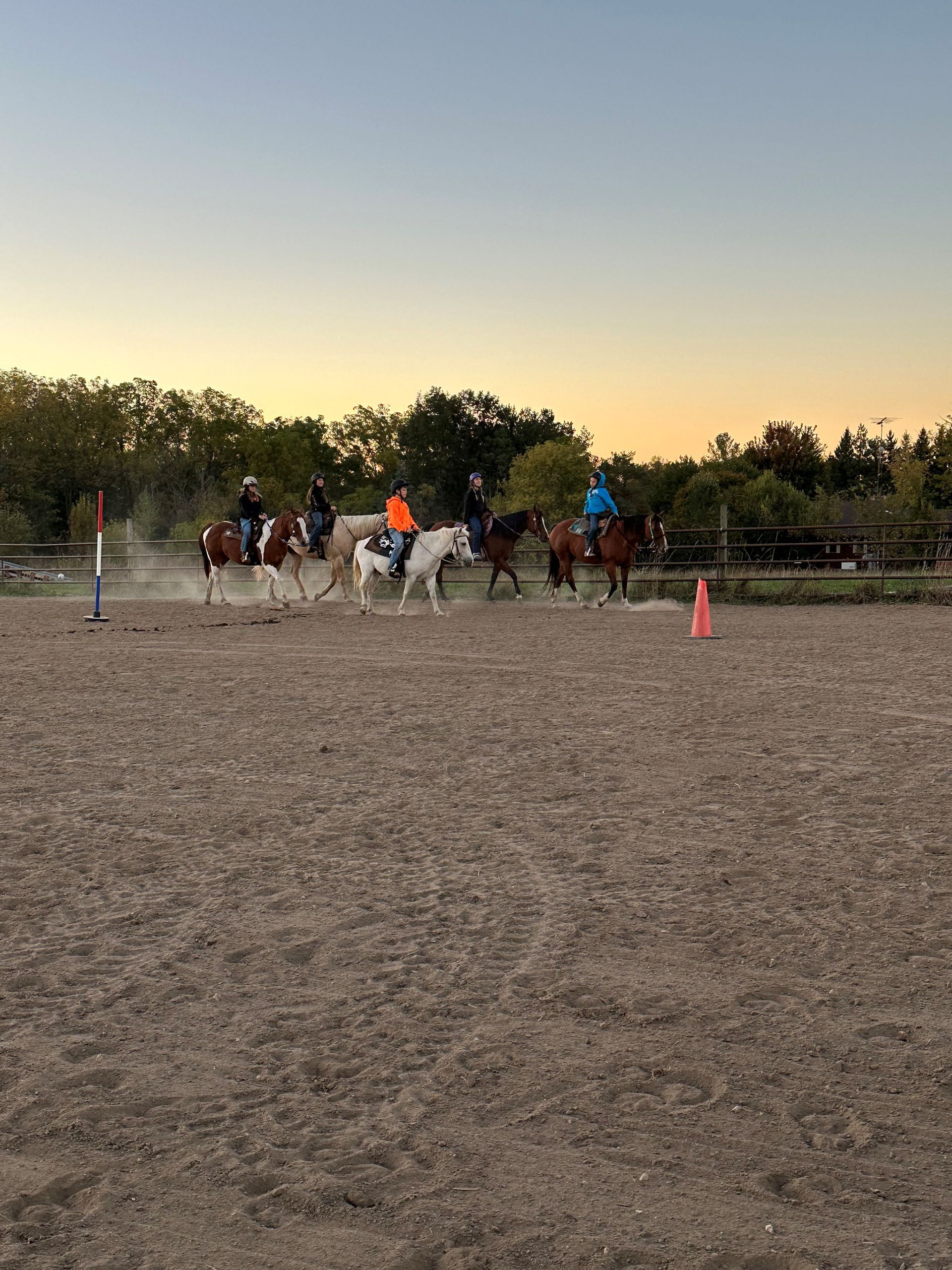 A group of people are riding horses in a dirt field.