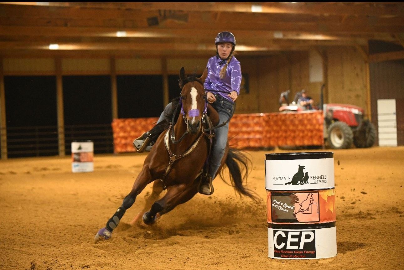 A woman is riding a horse around a barrel that says cep on it