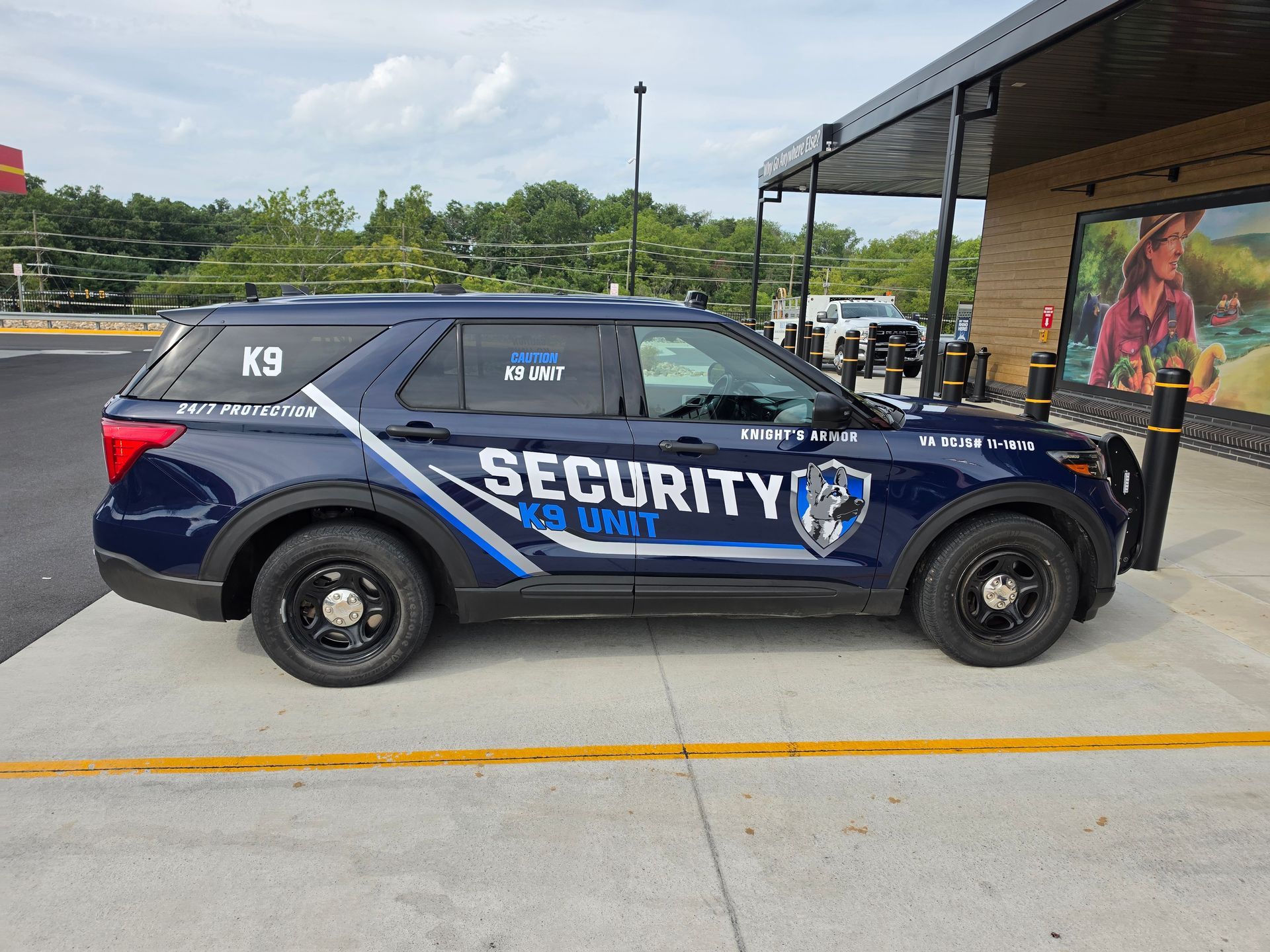 Security SUV parked outside a building, blue camouflage livery with large “SECURITY” text.