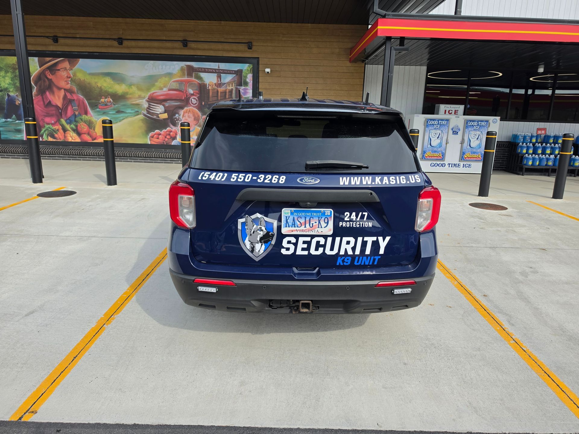 Blue security SUV parked under a covered area, rear view with large SECURITY text and logos.