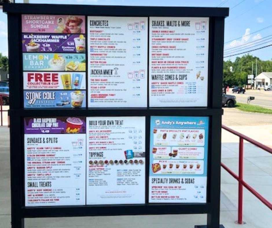 A menu board for Andy's Frozen Custard, listing various concretes, sundaes, shakes, and treats with pricing