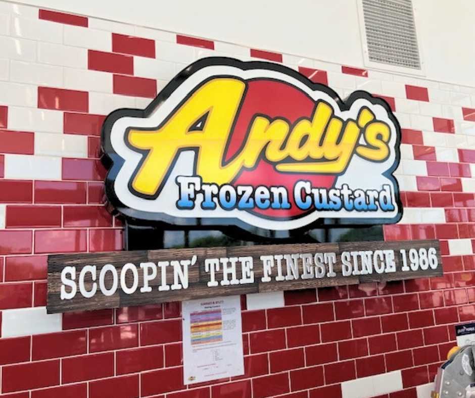 The Andy’s Frozen Custard logo mounted on a red and white tiled wall above a sign