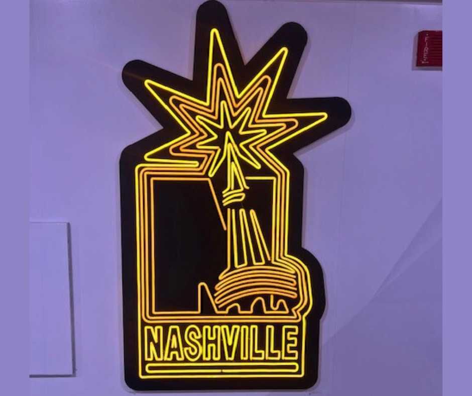 A yellow neon sign on a wall featuring an iconic Nashville skyline silhouette