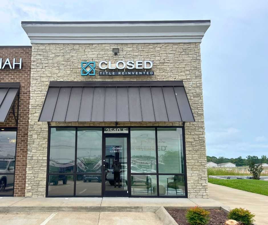 A stone-faced storefront for Closed title company with a dark metal awning and glass entry doors
