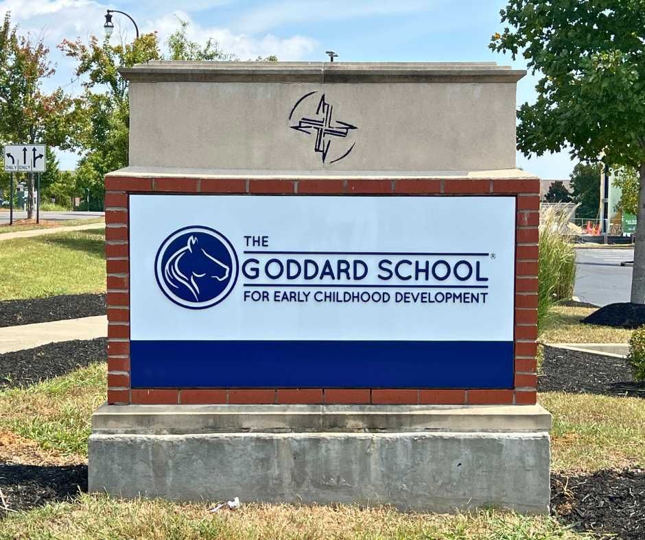 A brick and concrete monument sign for The Goddard School for Early Childhood Development outdoors on a sunny day
