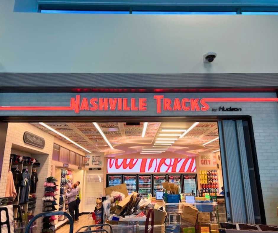 Storefront for Nashville Tracks by Hudson at an airport, featuring bright orange signage and a view of the shop interior