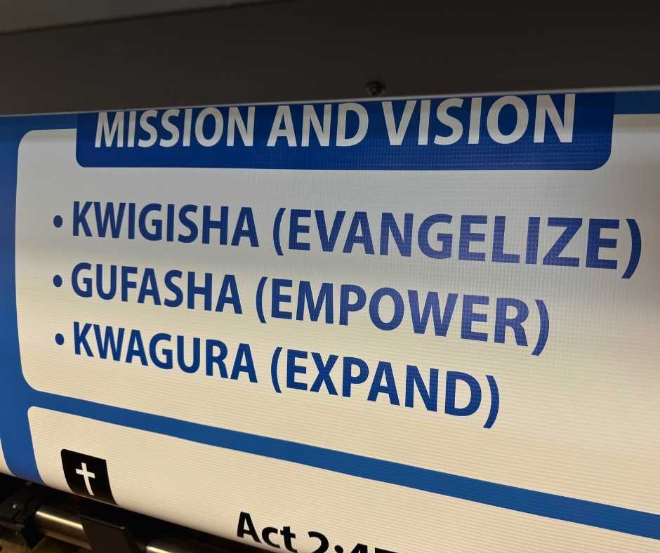 A sign listing mission and vision in Kinyarwanda and English: Kwigisha (Evangelize), Gufasha (Empower), Kwagura (Expand)