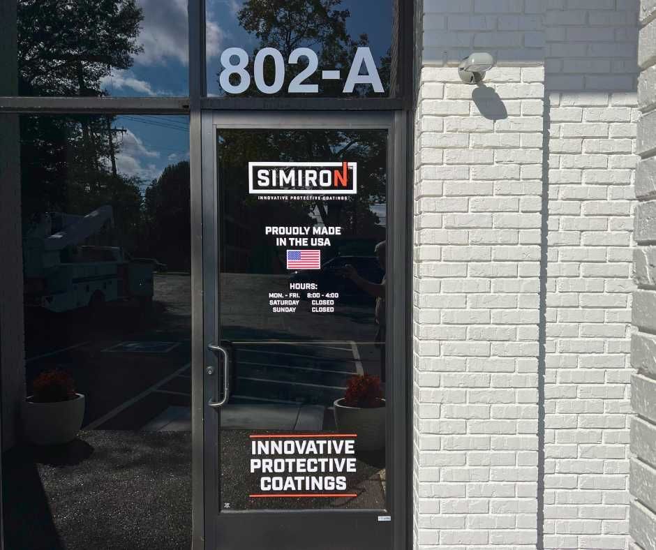 The storefront door of Simiron at 802-A, featuring company branding, Made in USA logo, business hours, and signage