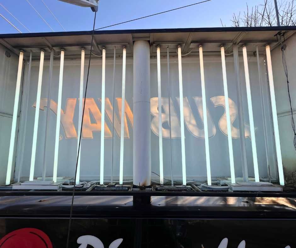 Open Subway sign illuminated by rows of vertical fluorescent bulbs