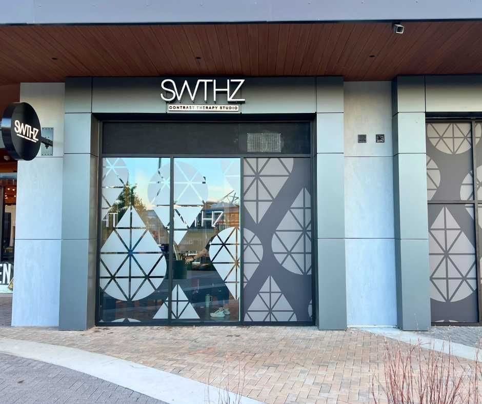 The storefront of a business named SWTHZ with geometric patterned glass, modern gray paneling, and a brick walkway
