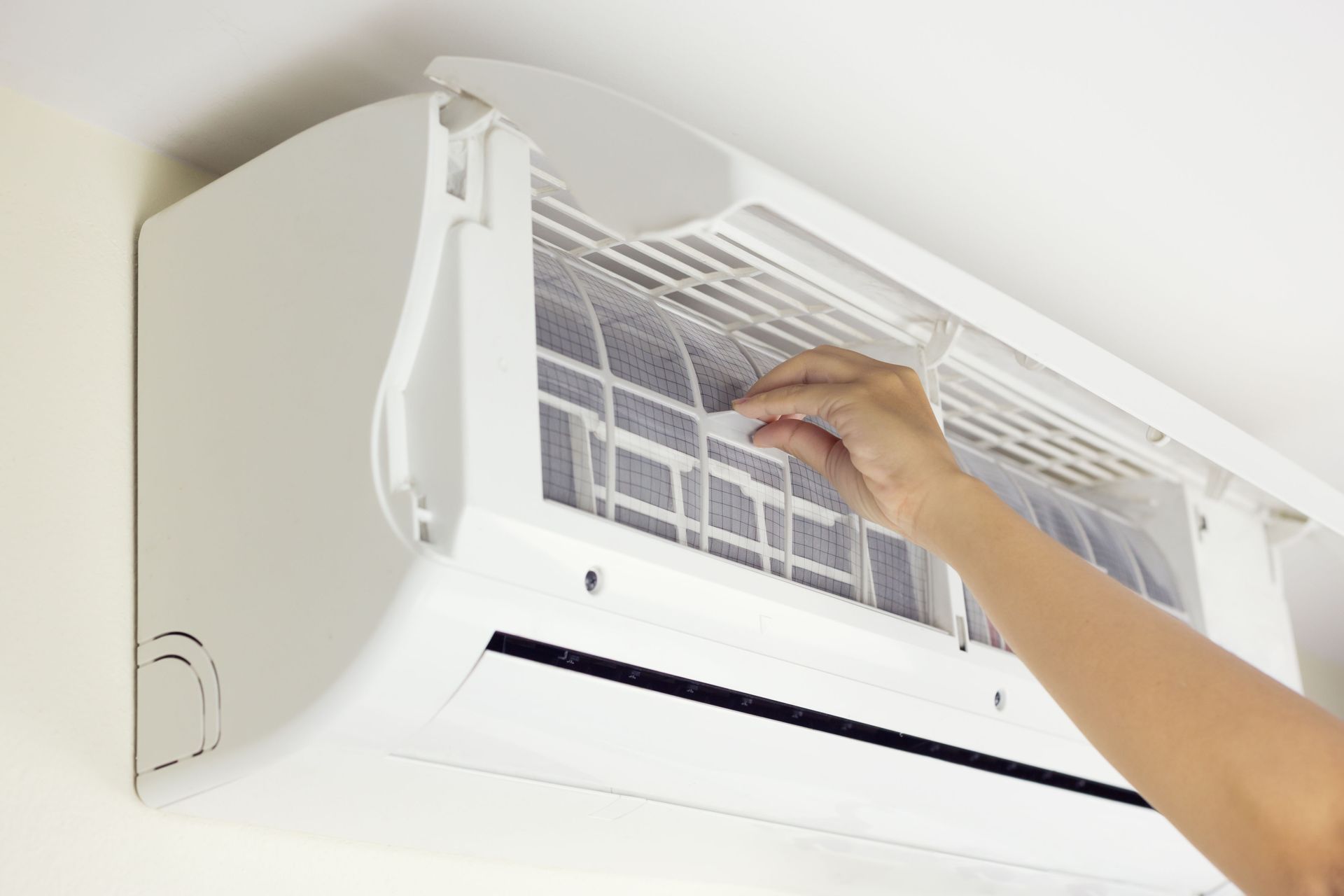 Hand cleaning a white wall-mounted air conditioner filter