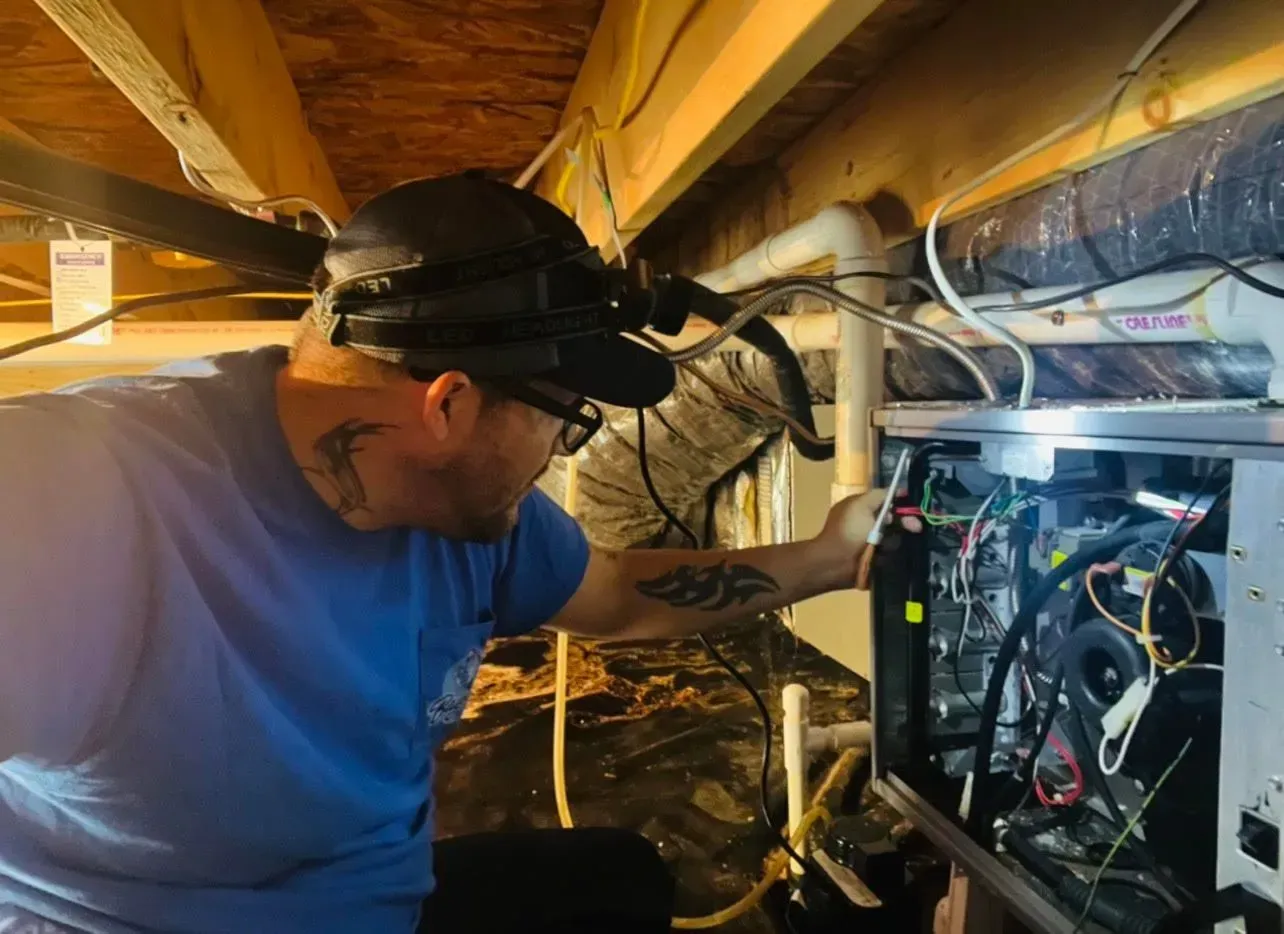 Technician inspecting wiring and equipment in a cramped attic space