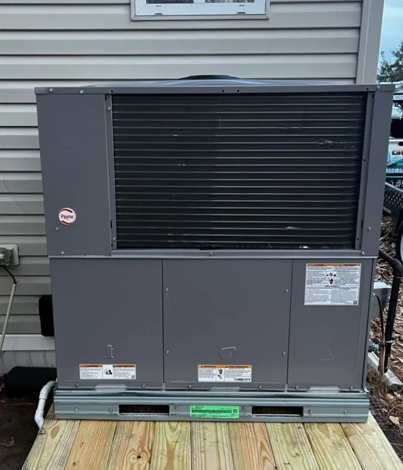 Large gray outdoor HVAC unit on a pallet beside a house exterior.