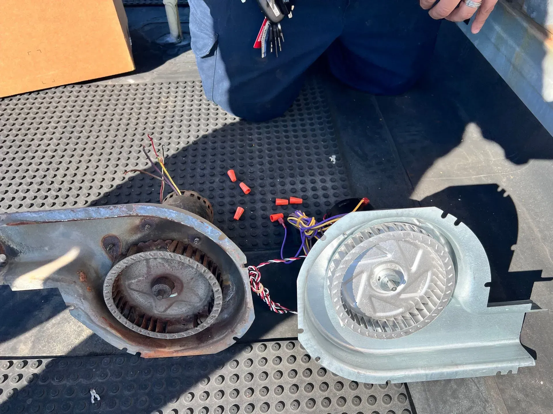 Two damaged metal blower fans on a black rubber mat, with red debris scattered nearby.