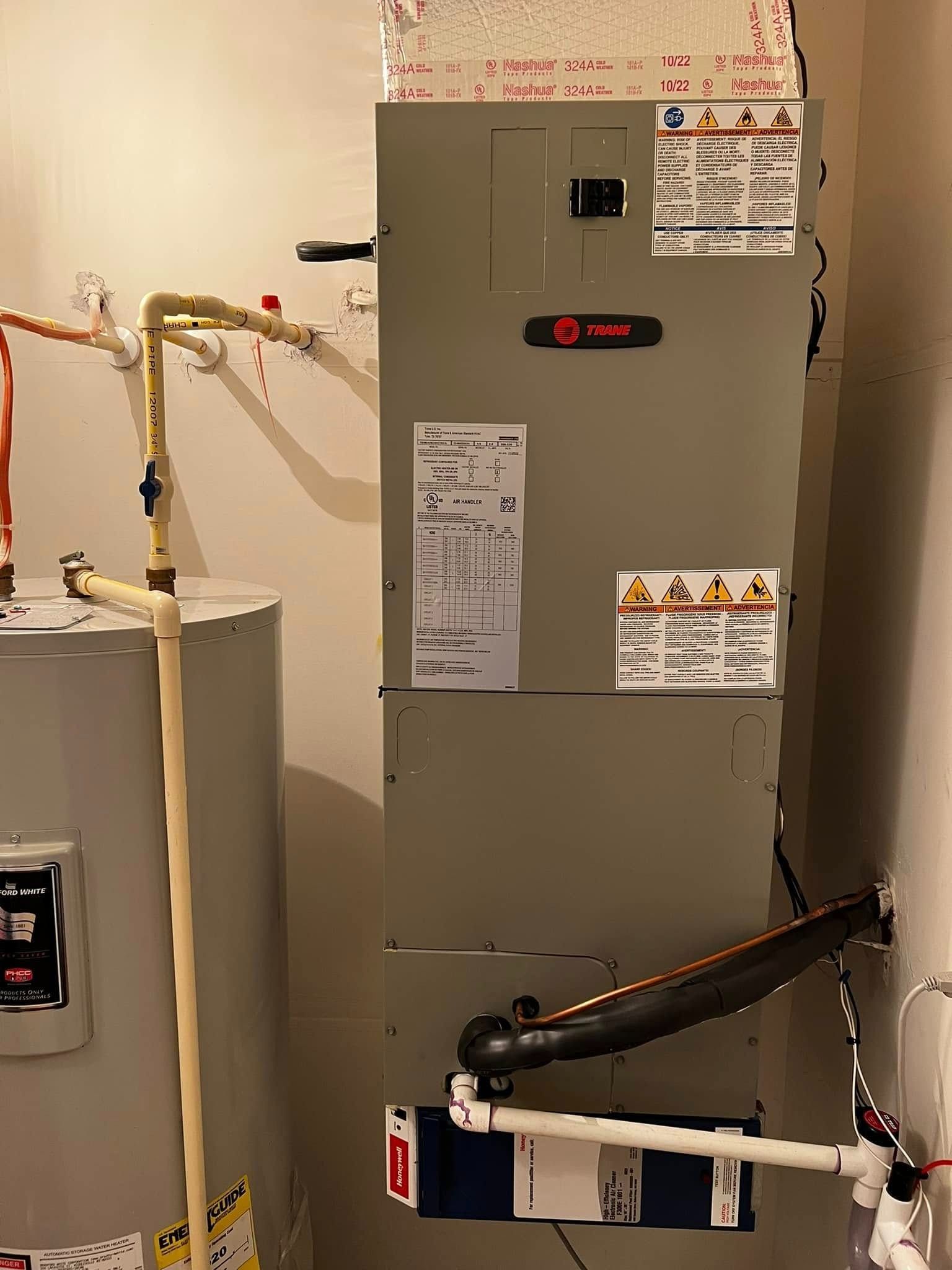 Water heater and furnace with visible pipes in a utility closet