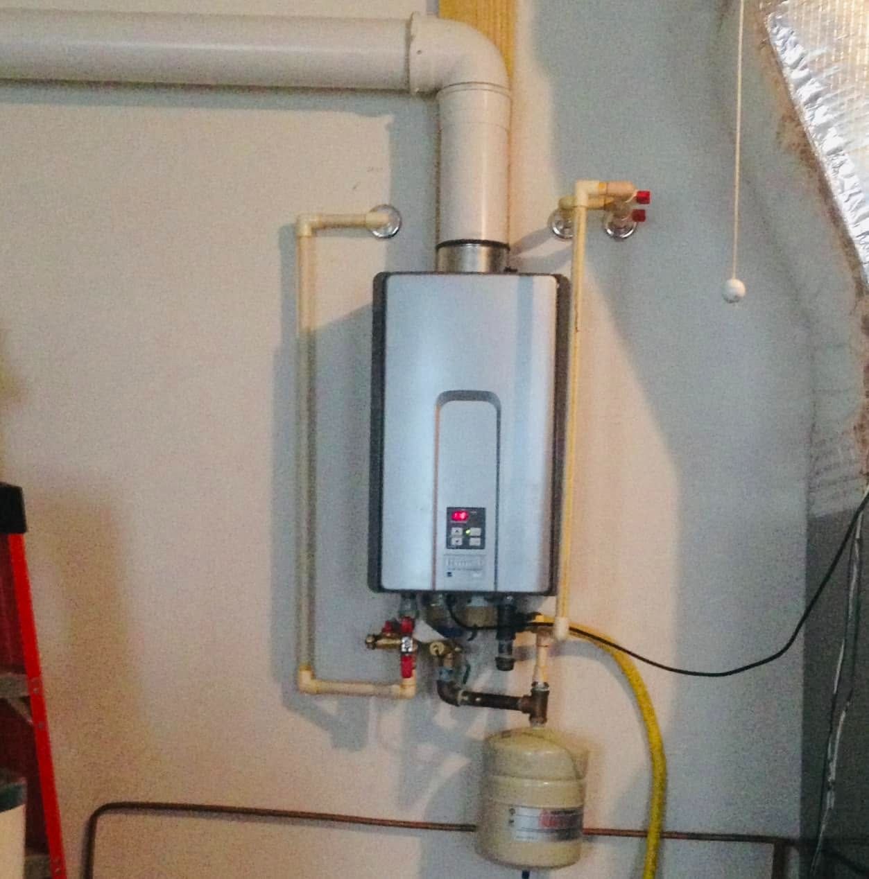 Wall-mounted tankless water heater with exposed pipes and a yellow gas line in a utility room.