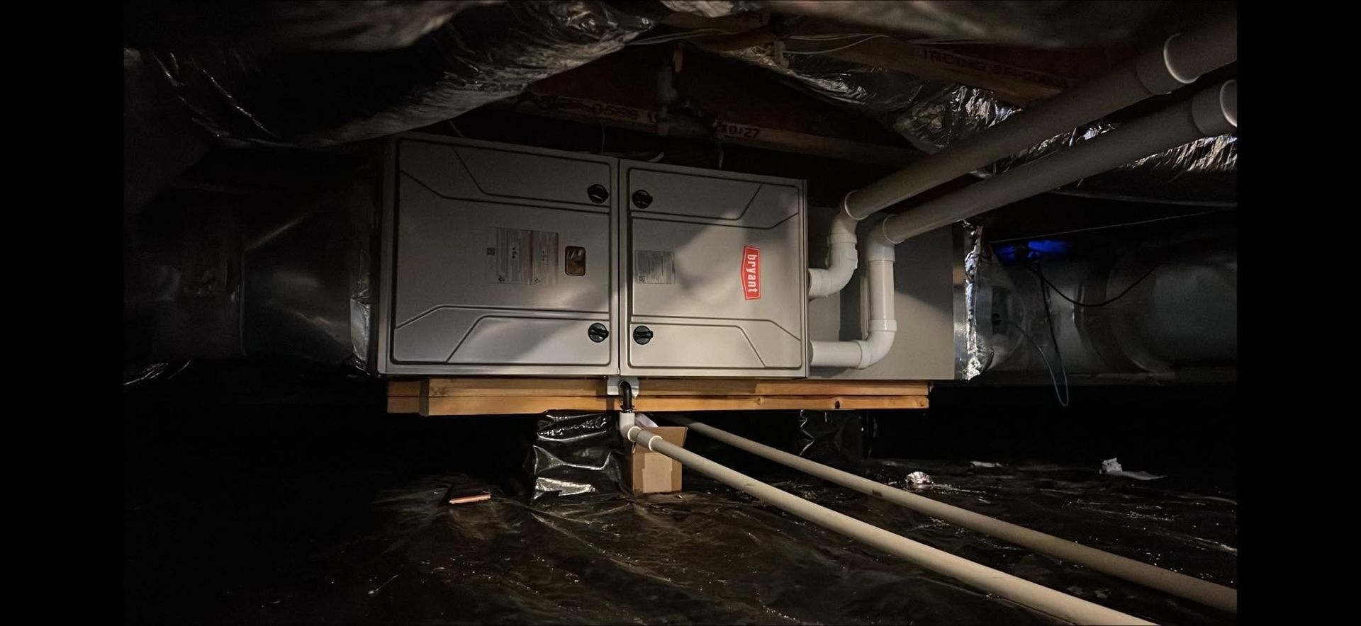 Industrial machine in a dark tunnel, with cables and pipes running along the floor and ceiling.
