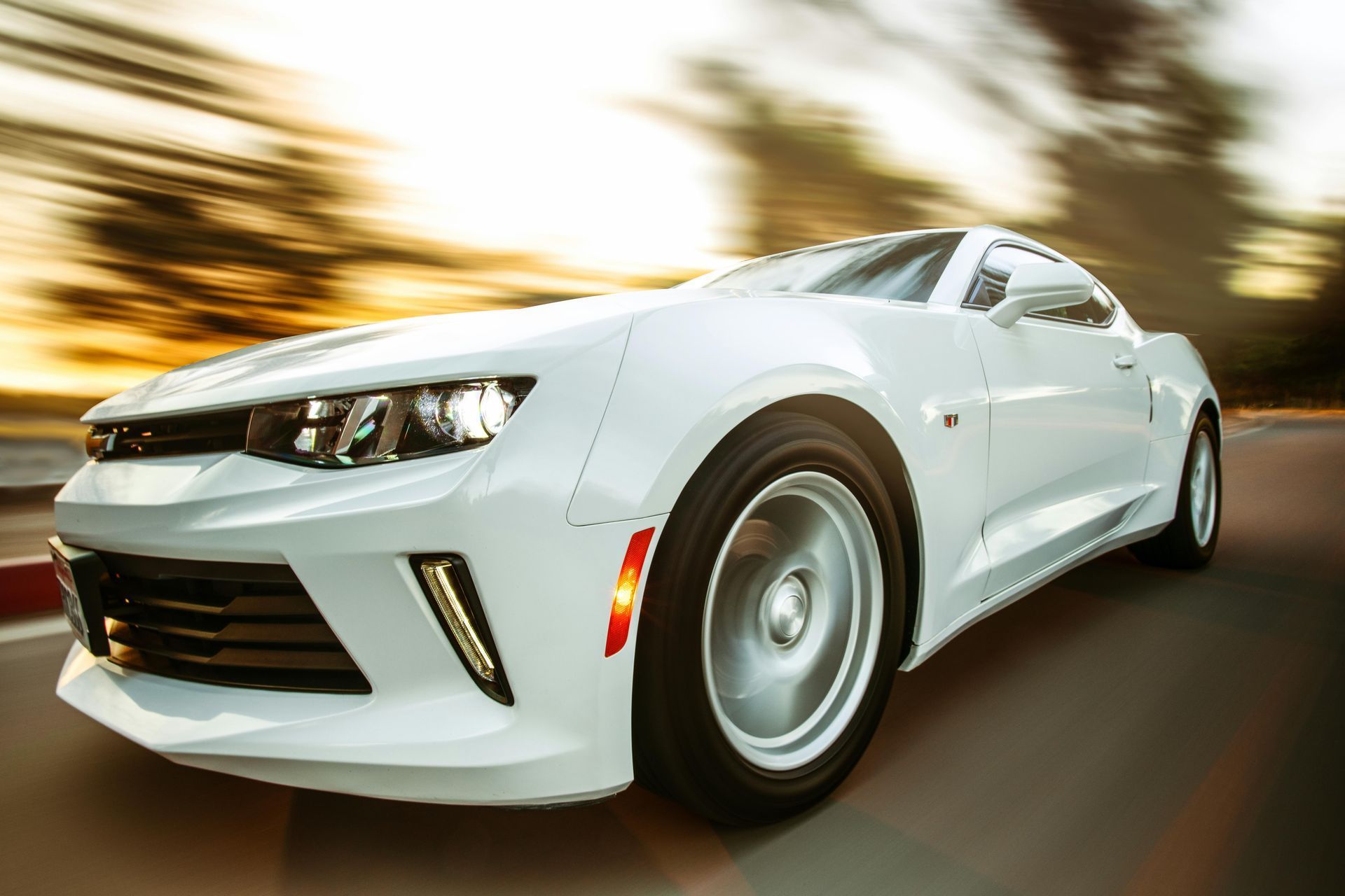 White sports car speeding on a road with motion-blurred background at sunset
