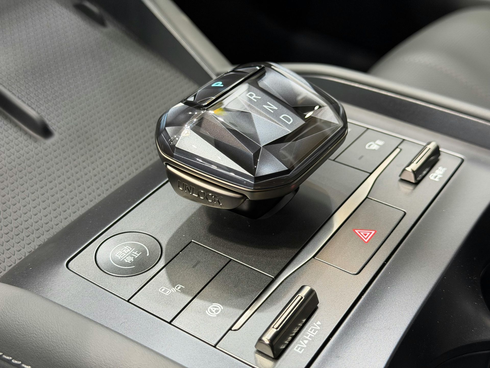 Car's center console with a rotary gear selector, drive mode button, and hazard light switch.