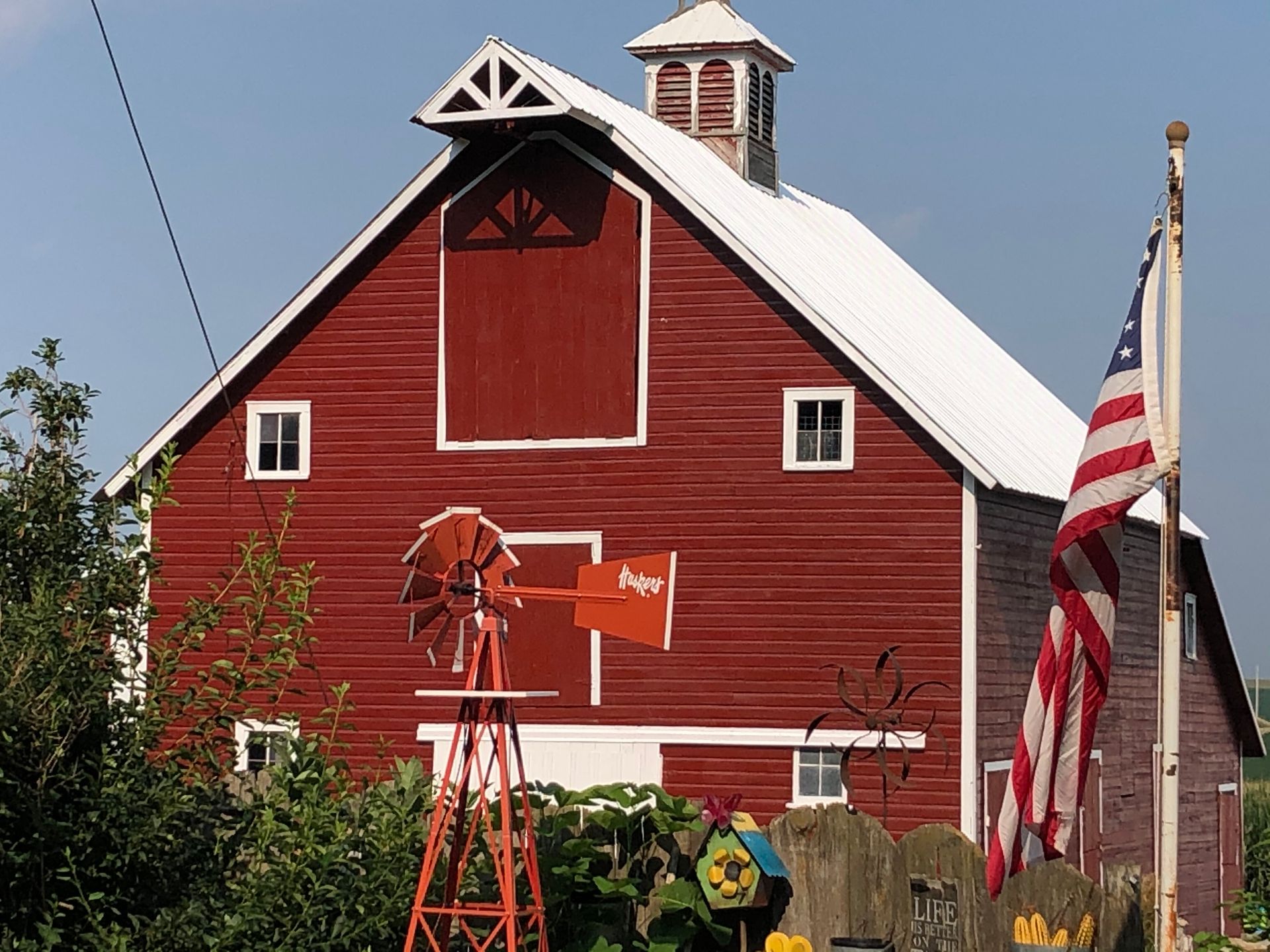 A red barn with a windmill in front of it.