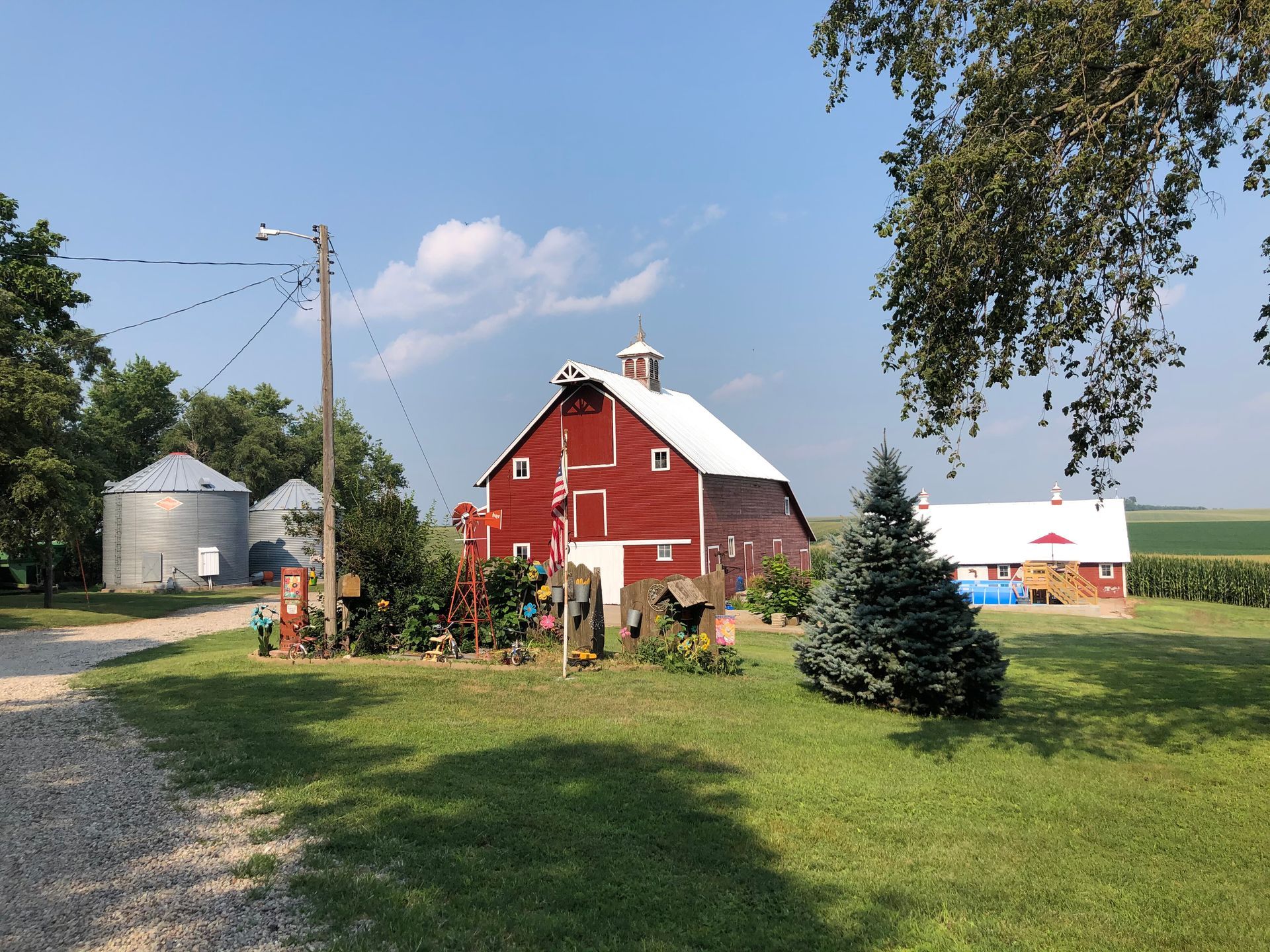 A red barn with a white roof is in the middle of a grassy field.