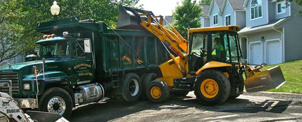 backhoe truck pouring into dump truck