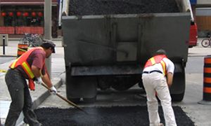 Two workers working with a tar truck