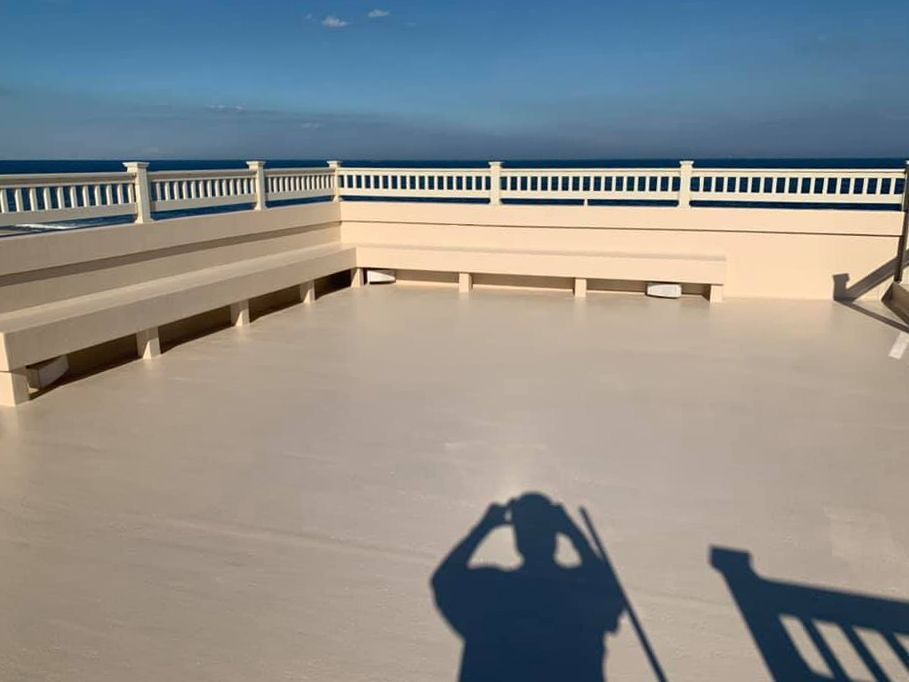 A shadow of a person standing on a balcony overlooking the ocean.
