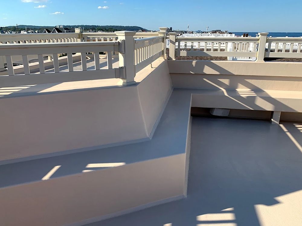 A balcony with a view of the ocean and a white railing