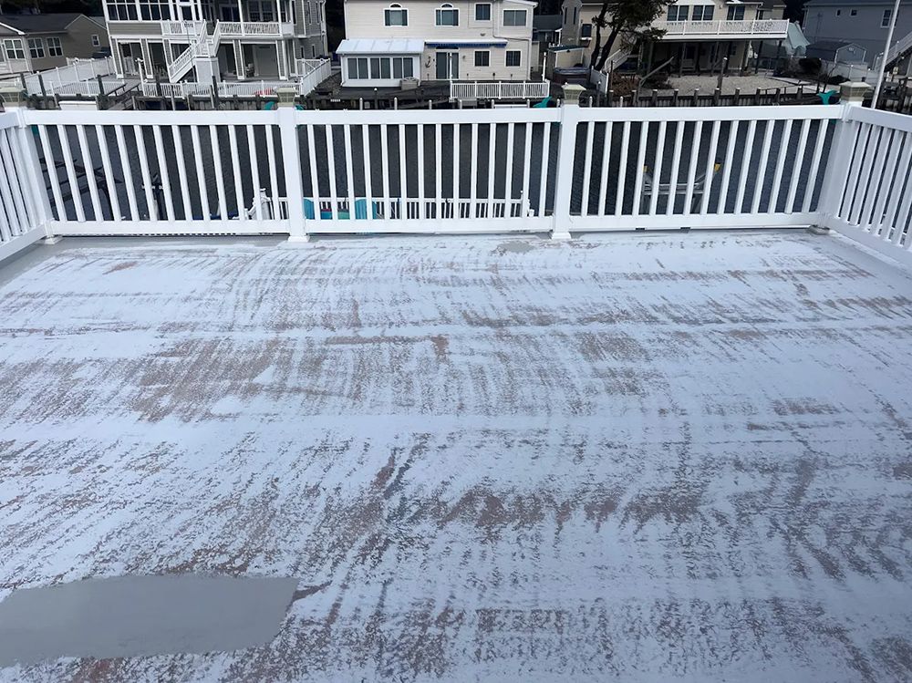 A rooftop deck with a white railing and a few houses in the background.