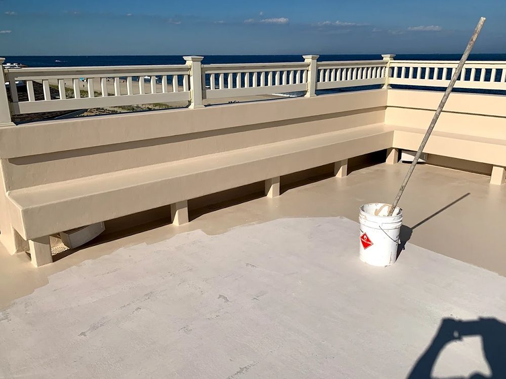 A bucket of paint is sitting on a roof next to a bench.