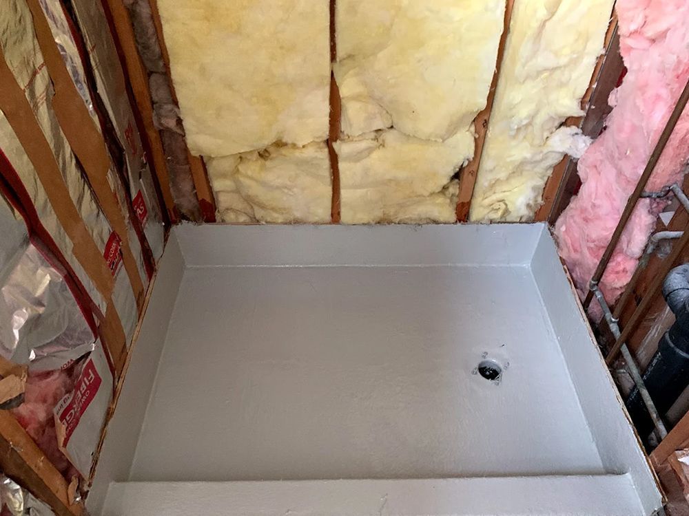 A shower stall in a bathroom with insulation on the walls and ceiling.