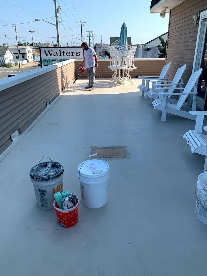 A man is cleaning a patio with buckets and chairs.