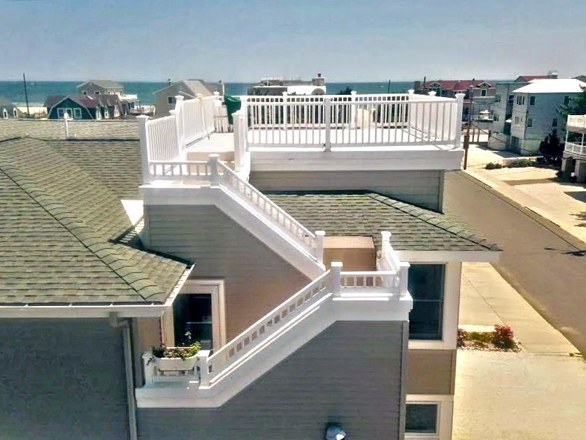 A house with stairs leading up to a balcony overlooking the ocean