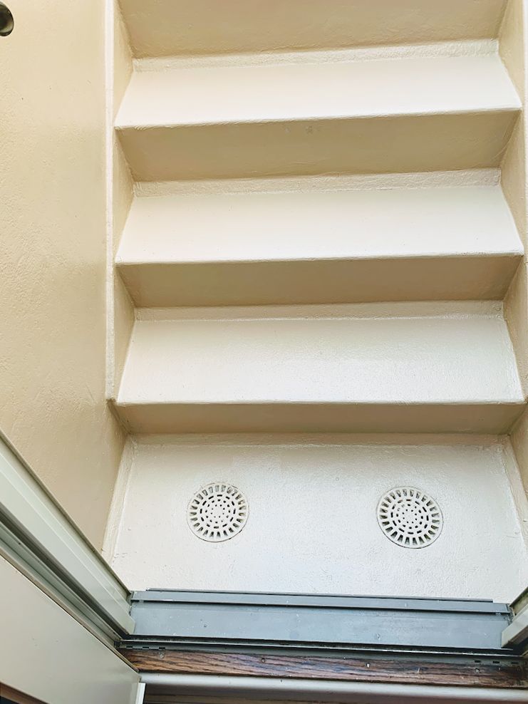A close up of a set of stairs with drains on the floor.