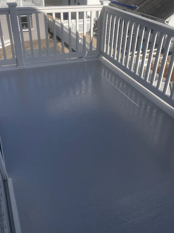 A balcony with a white railing and a gray floor.