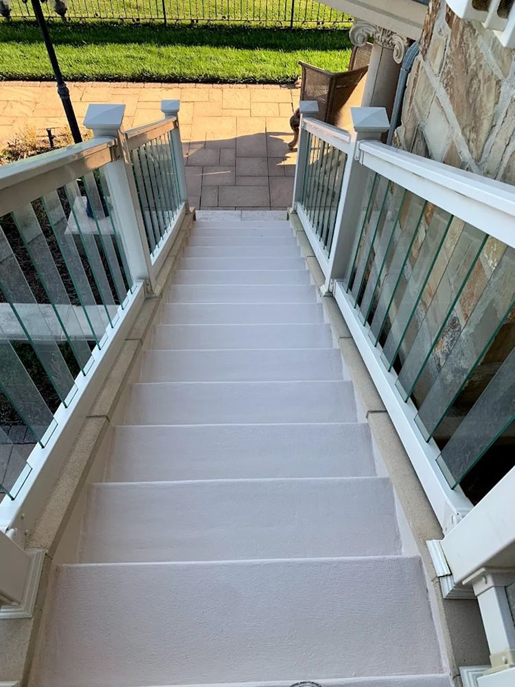 A set of stairs leading up to a patio with a white railing.