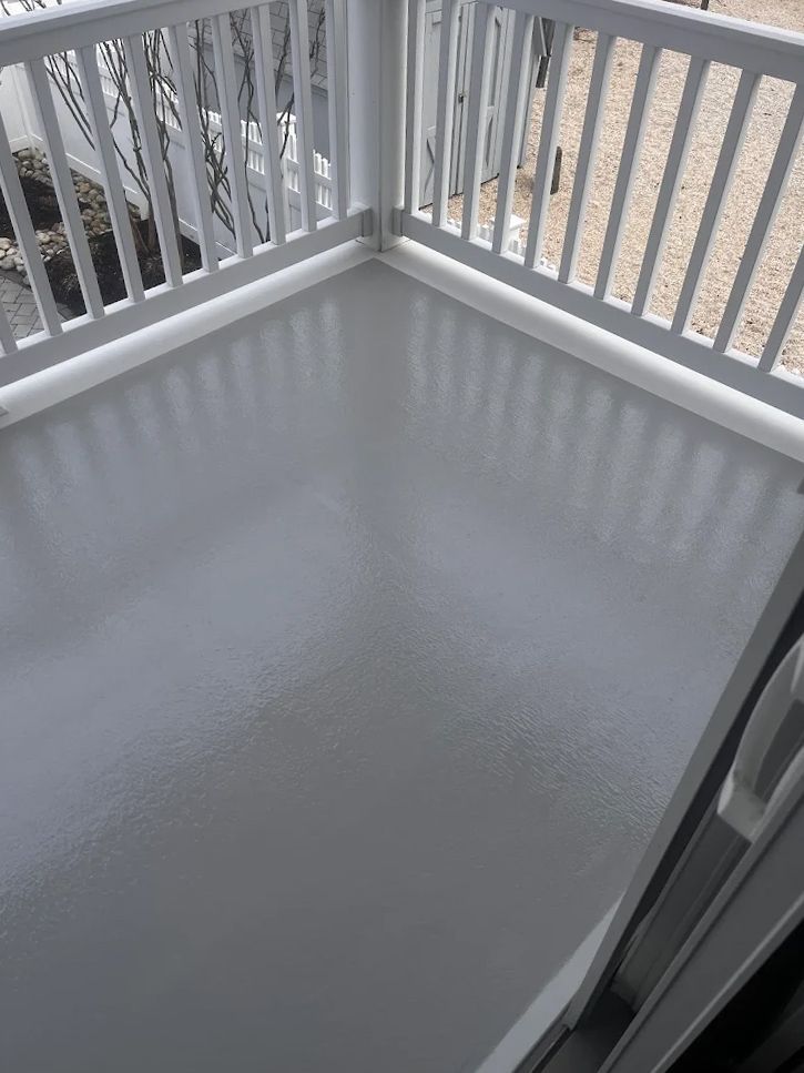 A balcony with a white railing and a gray floor.