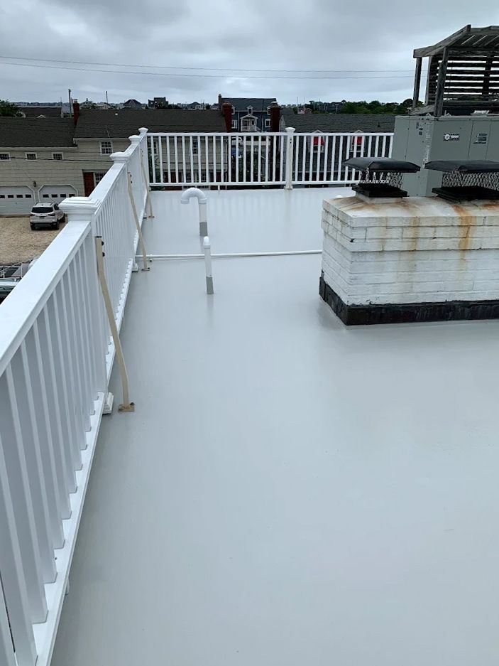 A rooftop deck with a white railing and a chimney.