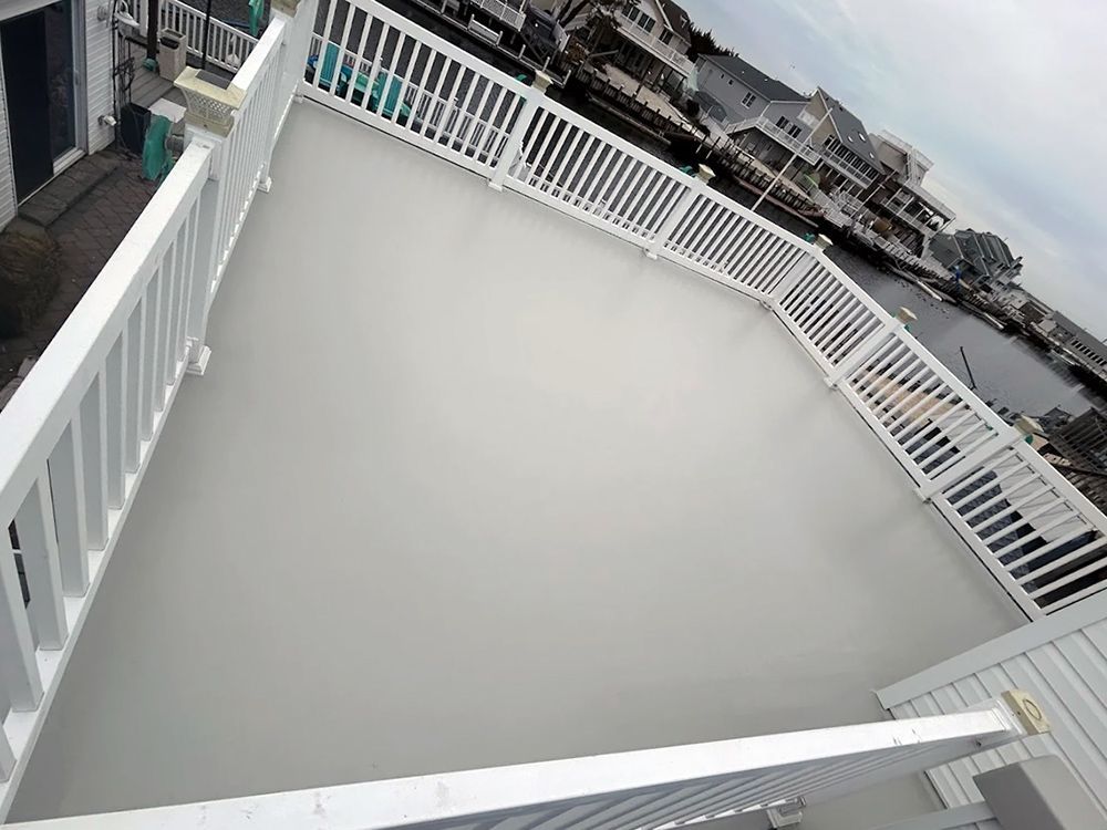 A large deck with a white railing and a view of the water.