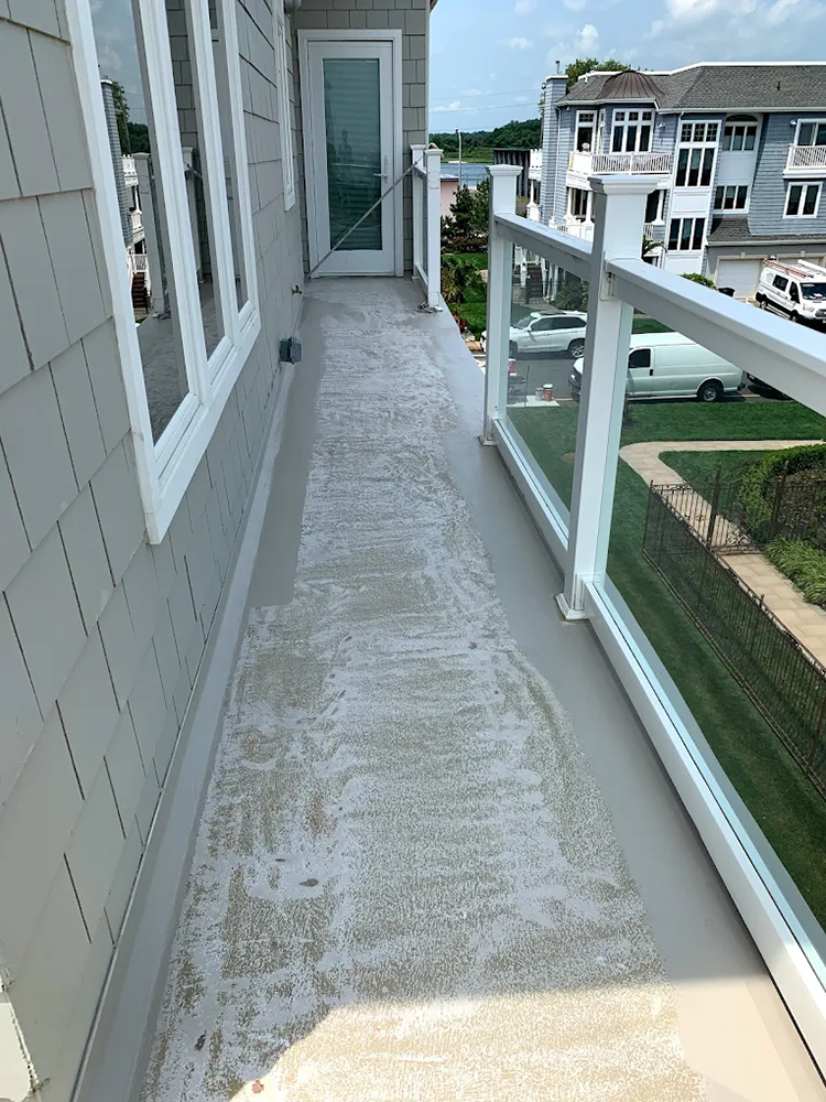 A walkway leading to a balcony with a glass railing and a door.