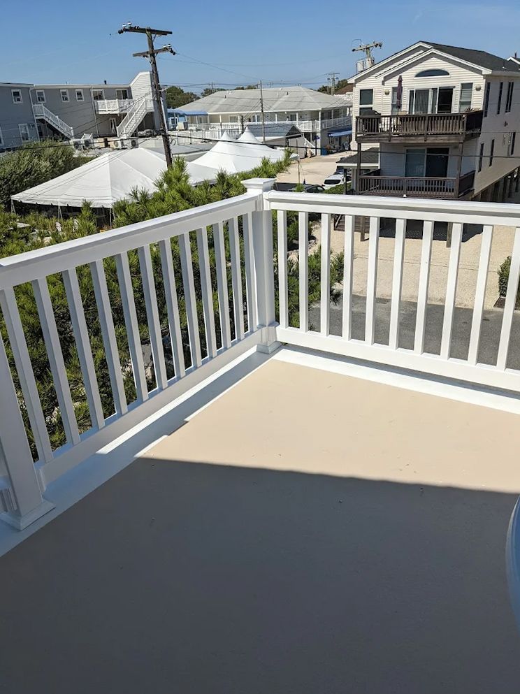 A balcony with a white railing and a view of a city.