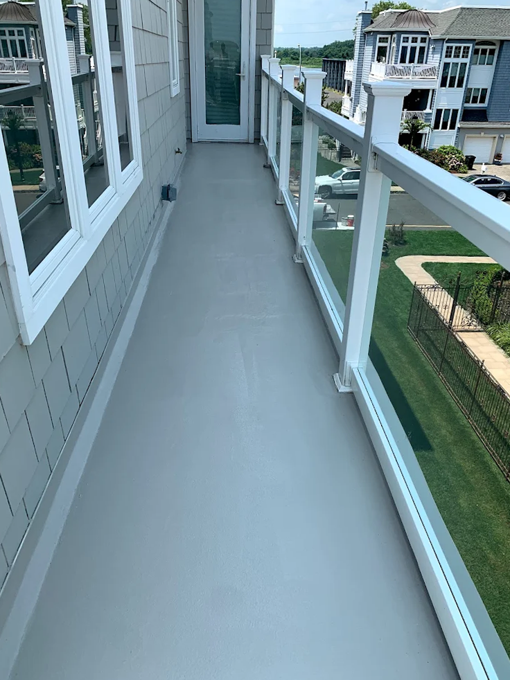 A balcony with a glass railing and a gray floor