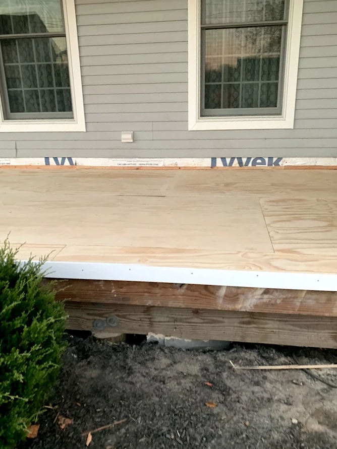 A wooden porch is being built on the side of a house.
