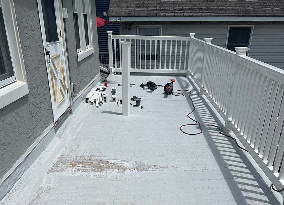 A white deck with a white railing is being built on the side of a house.