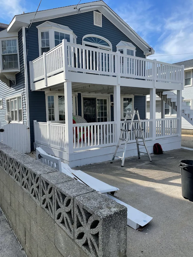 A blue house with a white deck is being painted