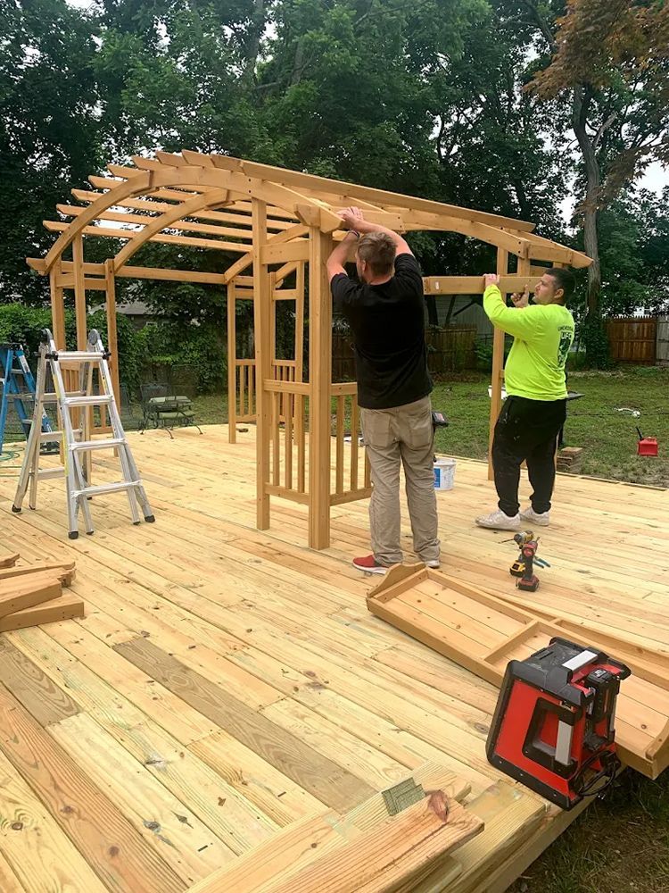 Two men are working on a wooden structure in a backyard.