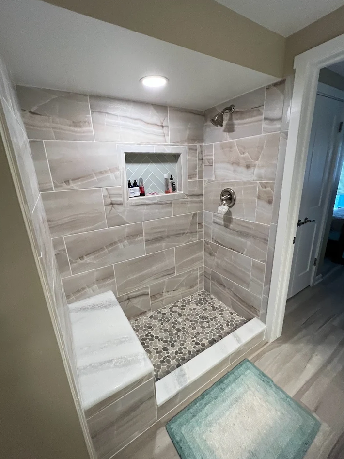 A bathroom with a walk in shower and a bench.