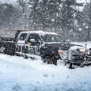 A truck is plowing snow on a snowy road.