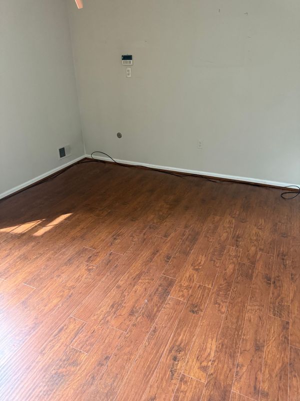 Empty room with brown laminate flooring and light gray walls.